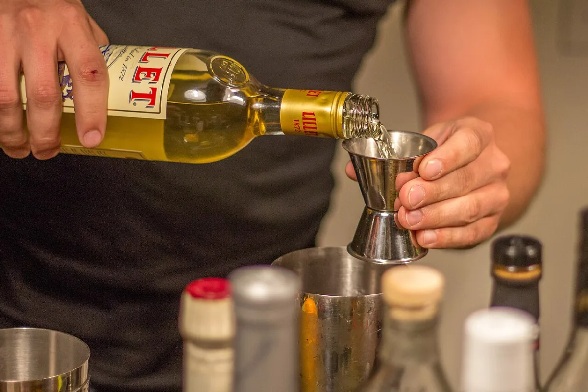 Barman schenkt drank met een jigger measure in een roestvrijstalen maatbeker